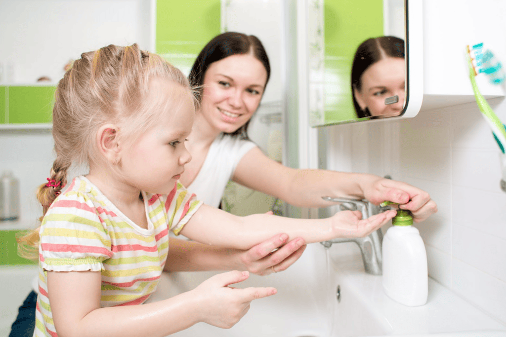 Child learning how to wash hands to eventually lead to this task being part of an independent morning routine.